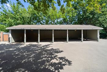 A large building with a grey roof and pillars is surrounded by trees.